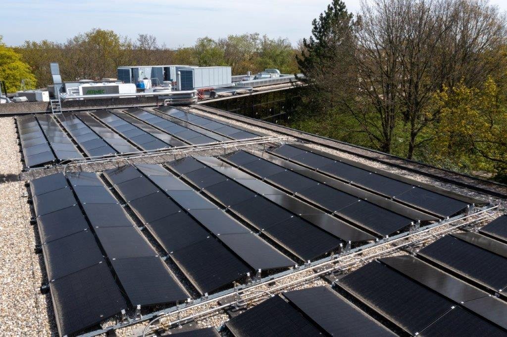 Hoe werkt een PVT-paneel: gestapelde PVT-panelen op een plat bedrijfsdak met blauwe lucht